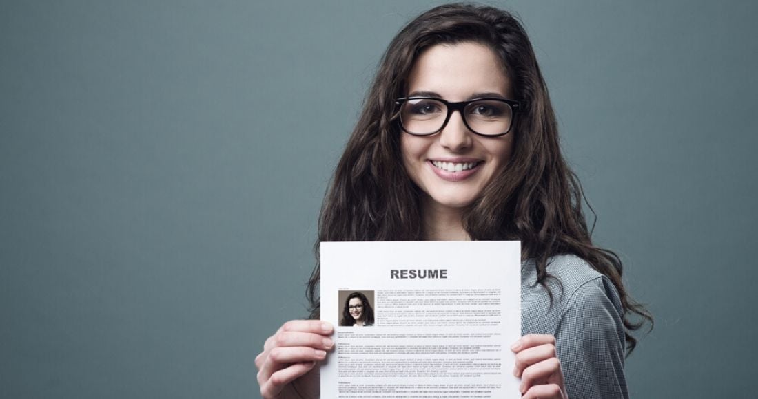 Joven sonriente exhibe su currículum vitae para hallar trabajo en tecnología mientras sonríe